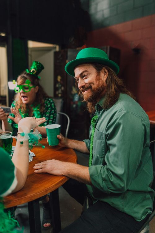 Free Group of friends celebrating St. Patrick's Day at a pub with drinks and green attire. Stock Photo
