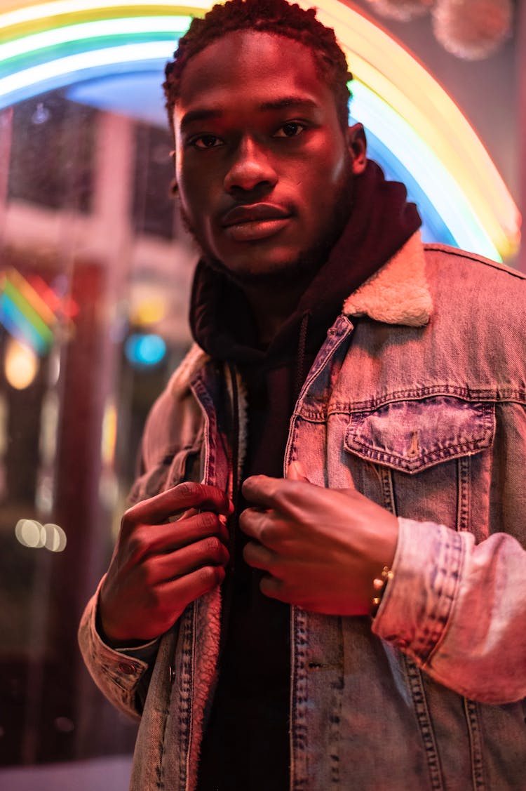 Black Male Near Illuminated Rainbow Signboard At Night Street