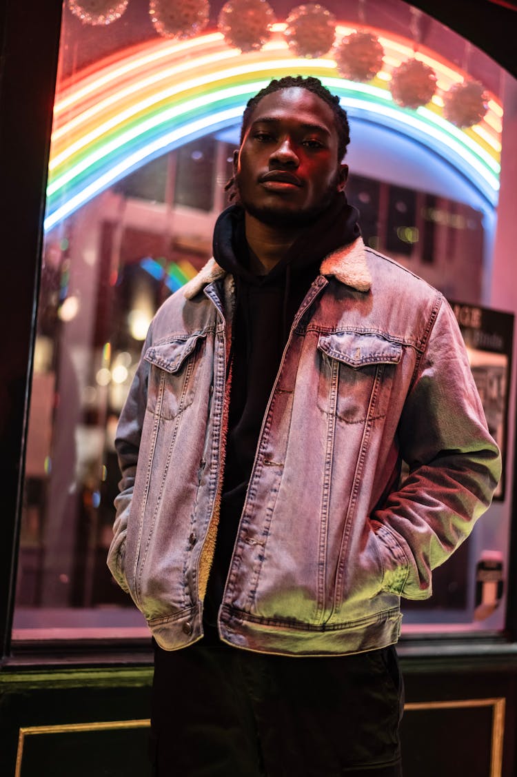 Black Guy In Street Near Glowing Rainbow Signboard In Building