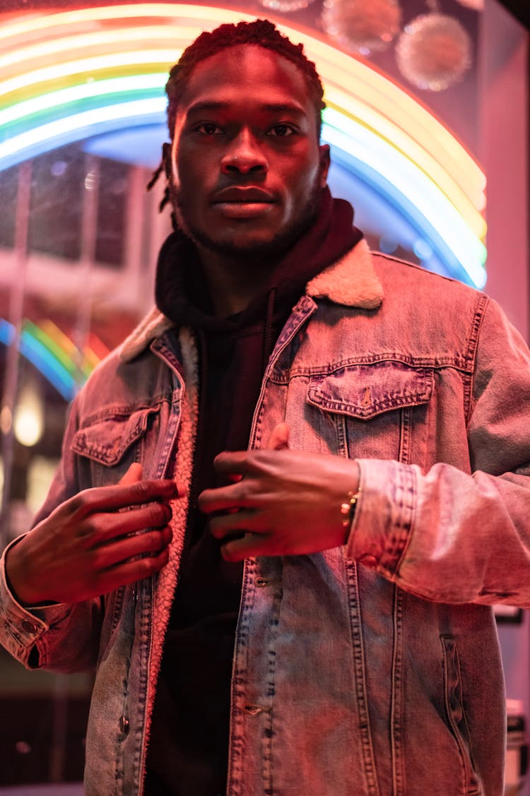 Black Male Near Illuminated Rainbow Signboard At Night Street