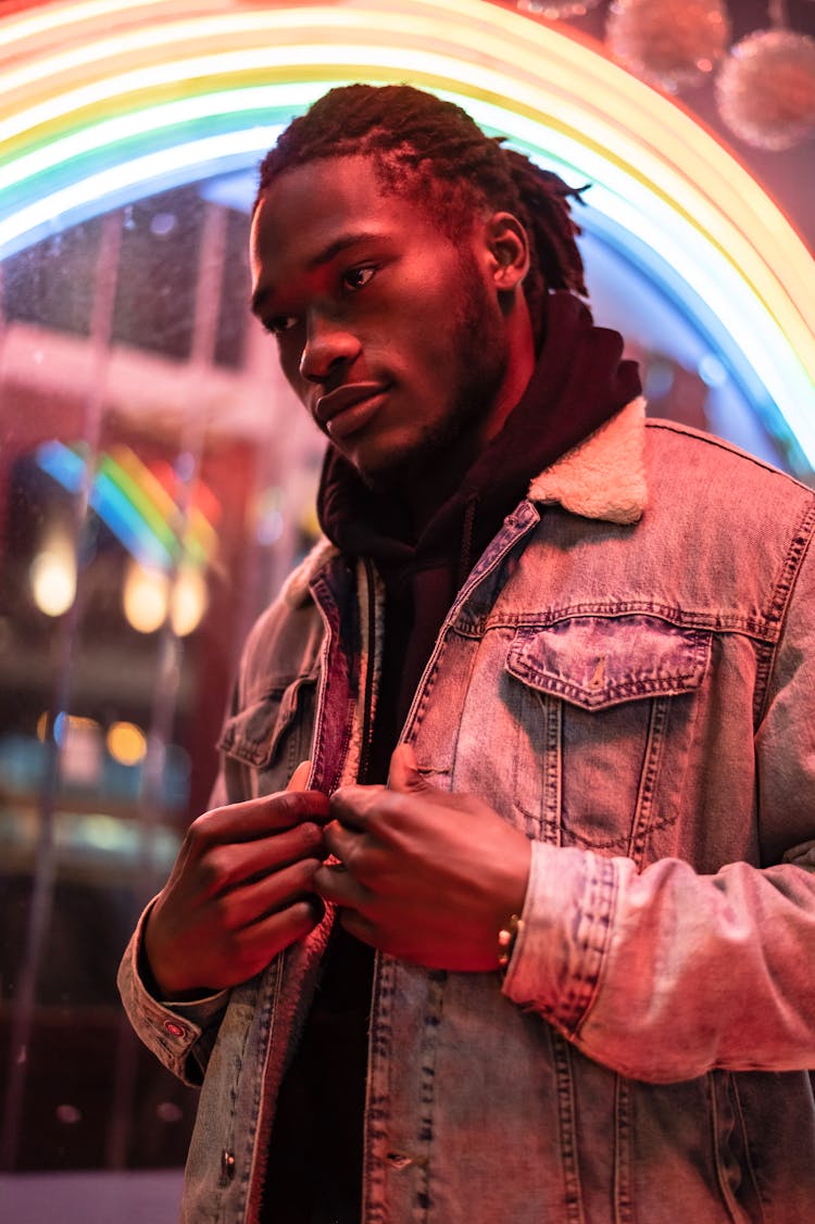 Black Male Near Illuminated Rainbow Signboard At Night Street