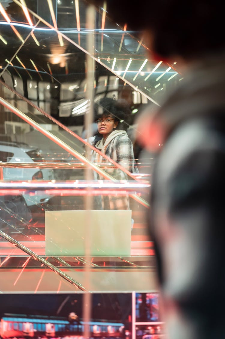 Glass Reflection Of Black Woman Near Shop With Escalator