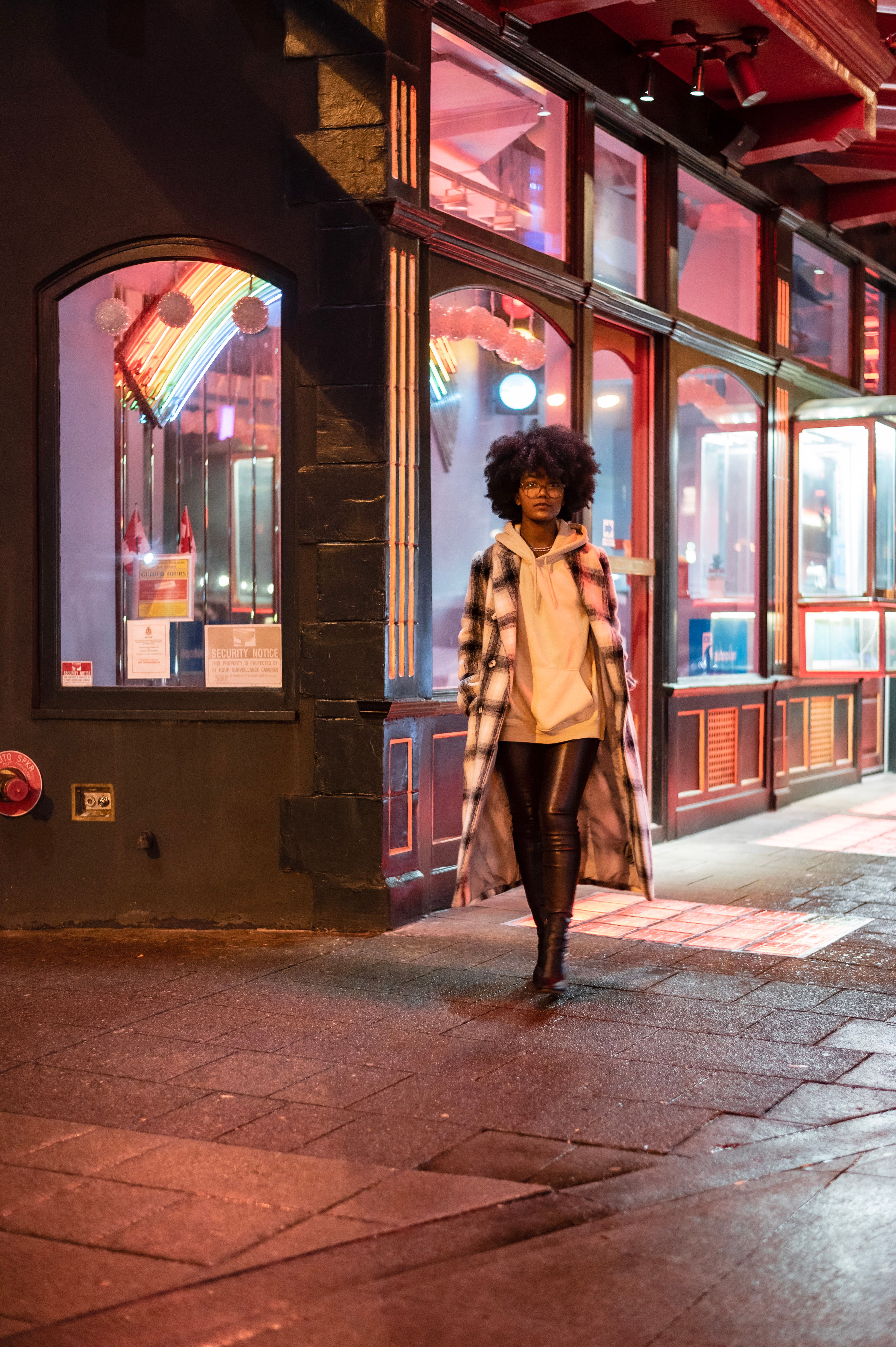 Black lady on city street near glowing building at night · Free Stock Photo