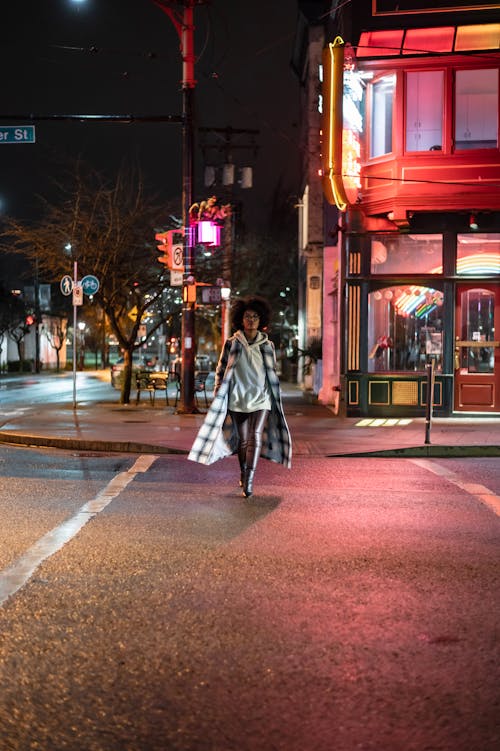 Black lady on road in street near building at night