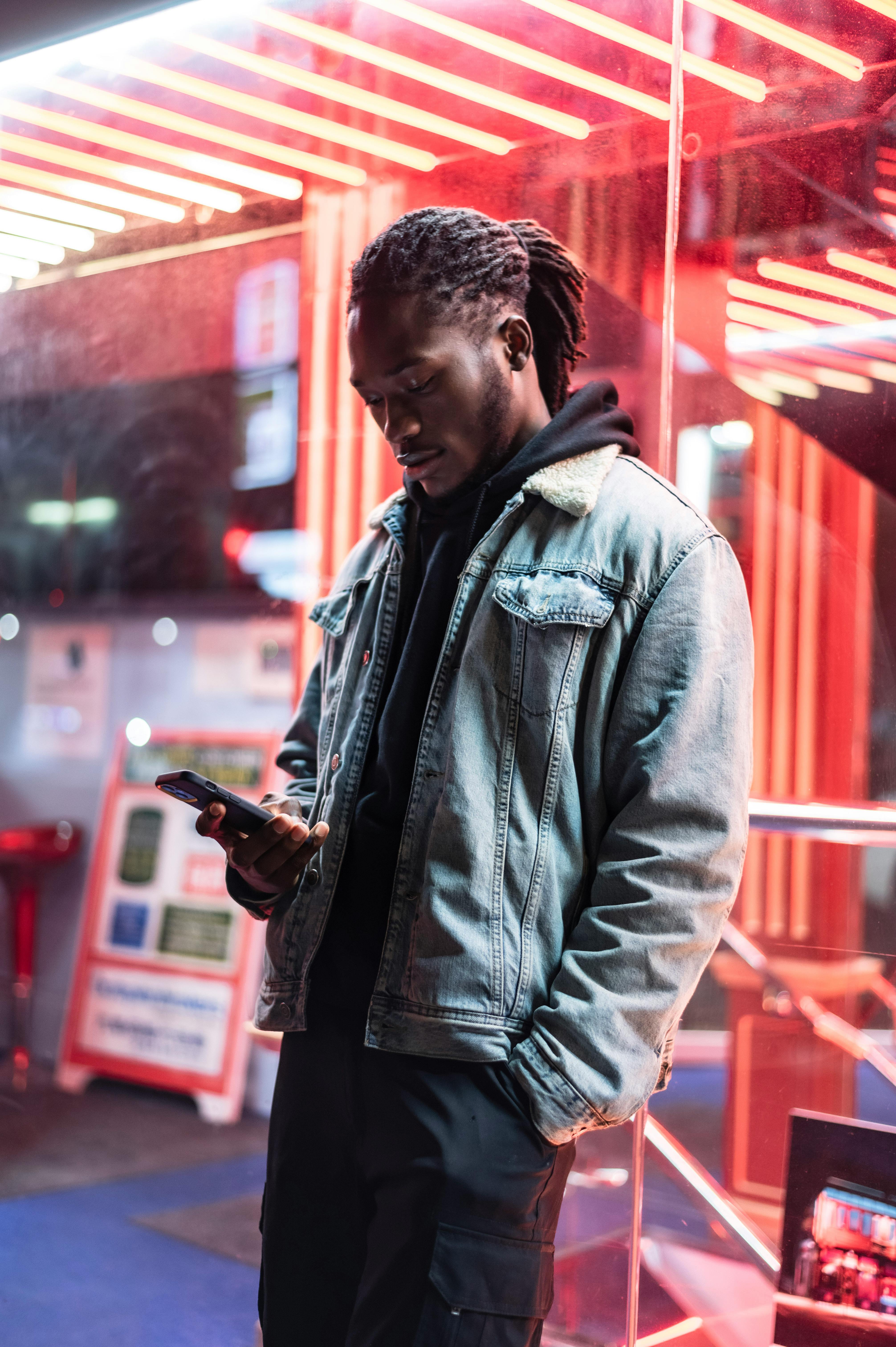 serious black man surfing smartphone near glass wall