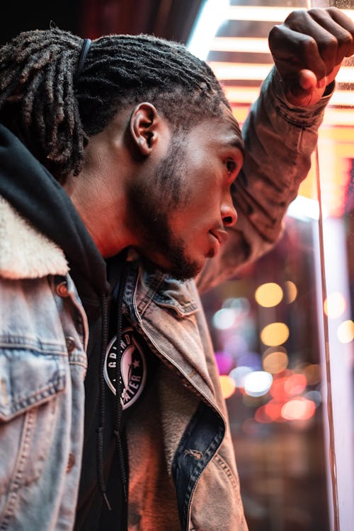 Serious black man near glass wall on street