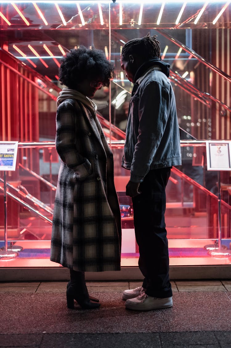 Displeased Black Couple Standing Near Glass Wall At Night