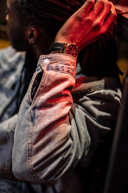 High angle side view of crop African American male in casual clothes and wristwatch touching dreadlocks