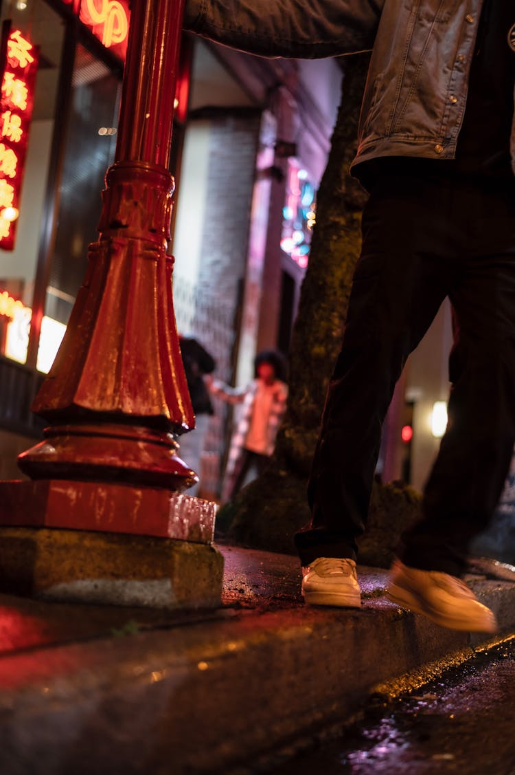 Man Standing Near Streetlamp On Street At Night