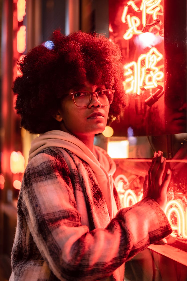 Serious Black Woman Near Building With Glowing Signboards