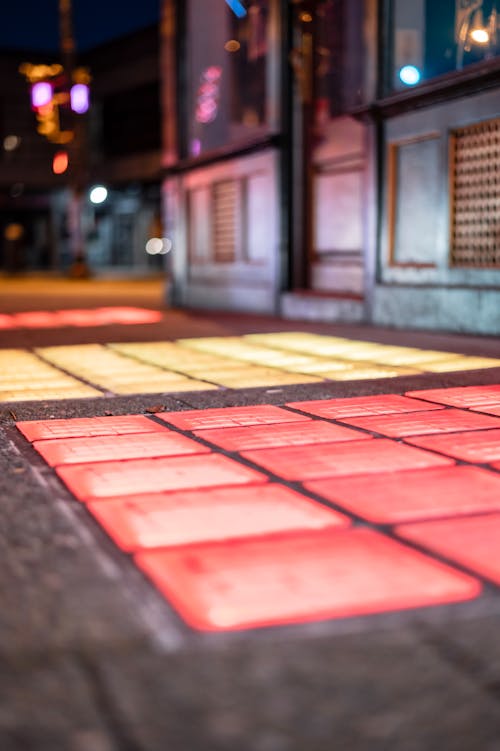 Rows of colorful tiles on empty walkway with building facade in city at dusk on blurred background