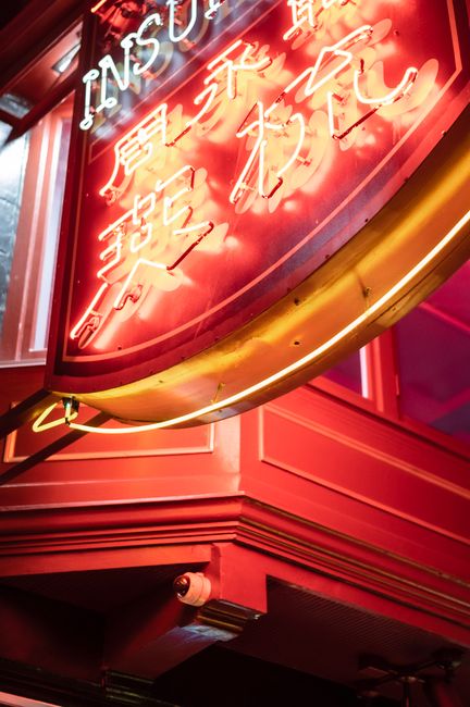 Low angle of hieroglyphs and title on neon signboard on building wall in night city