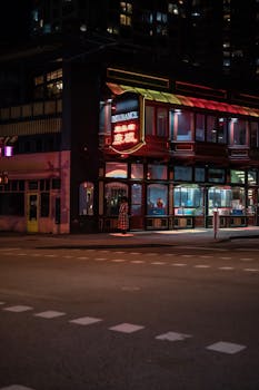 A vibrant city scene at night featuring a neon-lit building with an insurance sign in the urban landscape.