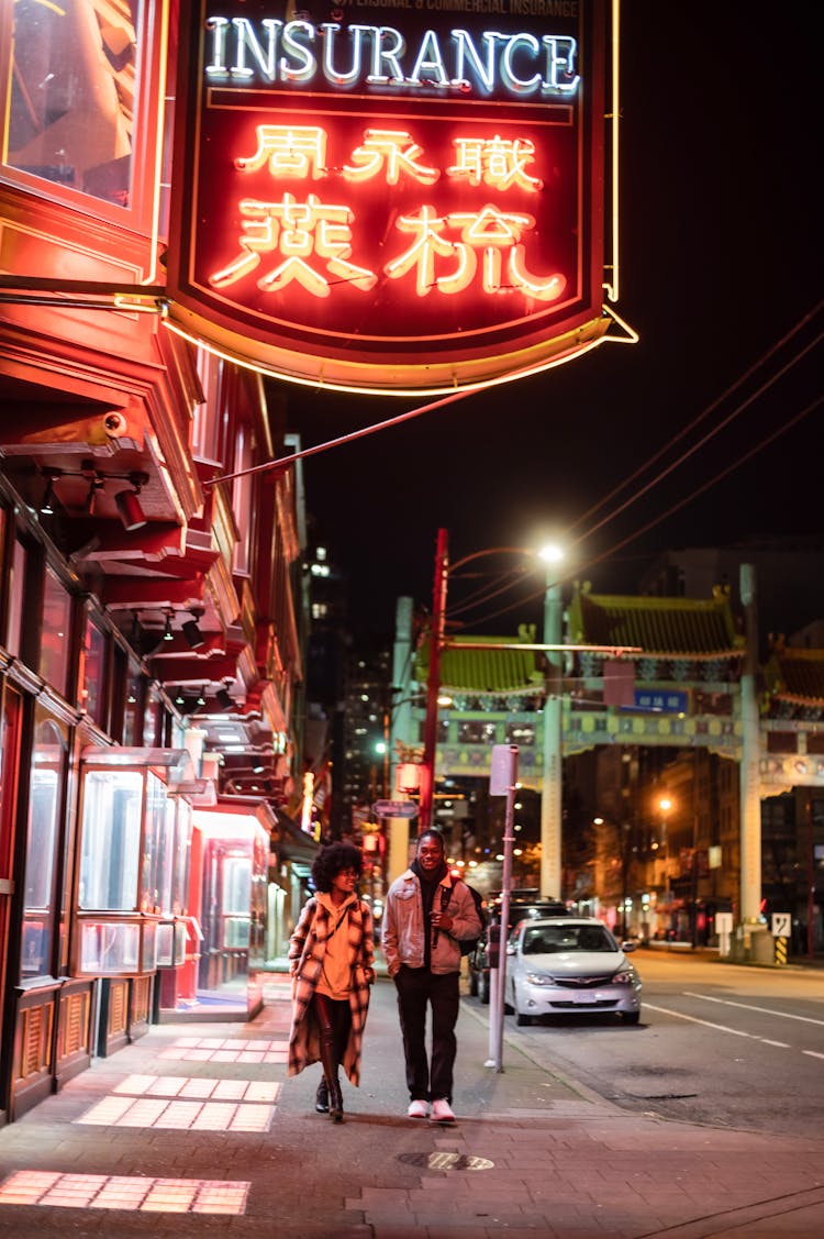 Man And Woman Walking In City At Night