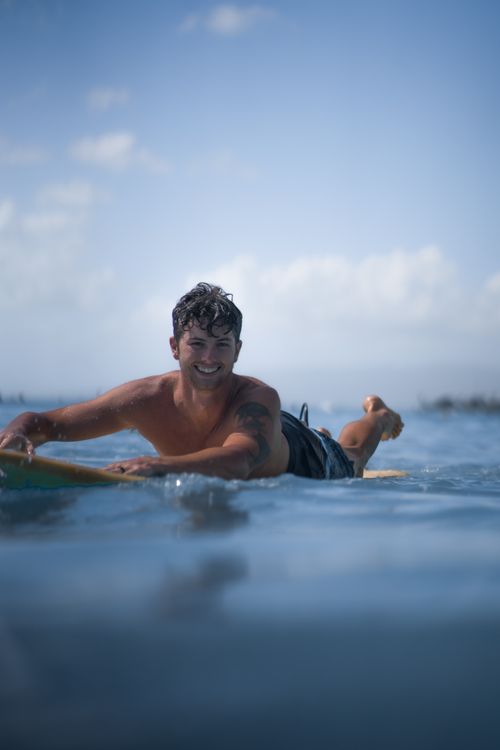 Free Happy shirtless man lying on surfing board and floating on sea water in sunlight looking at camera Stock Photo