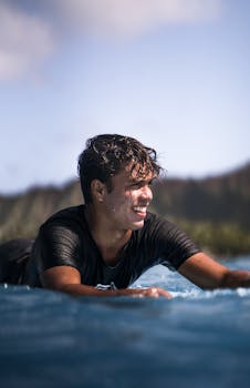 Cheerful man surfing in ocean waves, exuding joy and freedom under the summer sun.