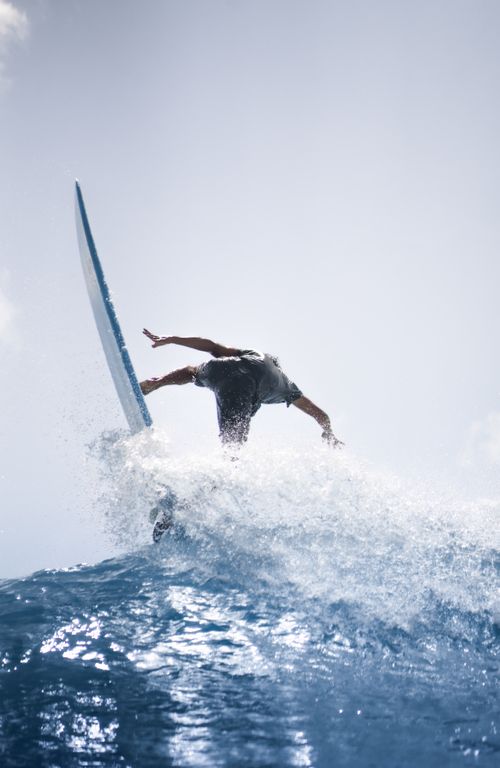 Free Back view of unrecognizable person in wetsuit balancing on board riding wave in blue sea Stock Photo