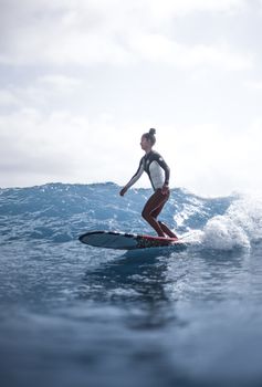 A woman skillfully rides a wave on her surfboard in the open ocean, showcasing surfing skills and balance.