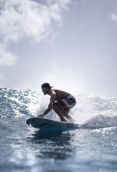 A man skillfully rides a surfboard on a large ocean wave under a clear sky.