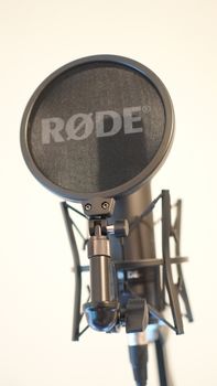 Close-up of a professional microphone with a pop filter, ideal for audio recording settings.