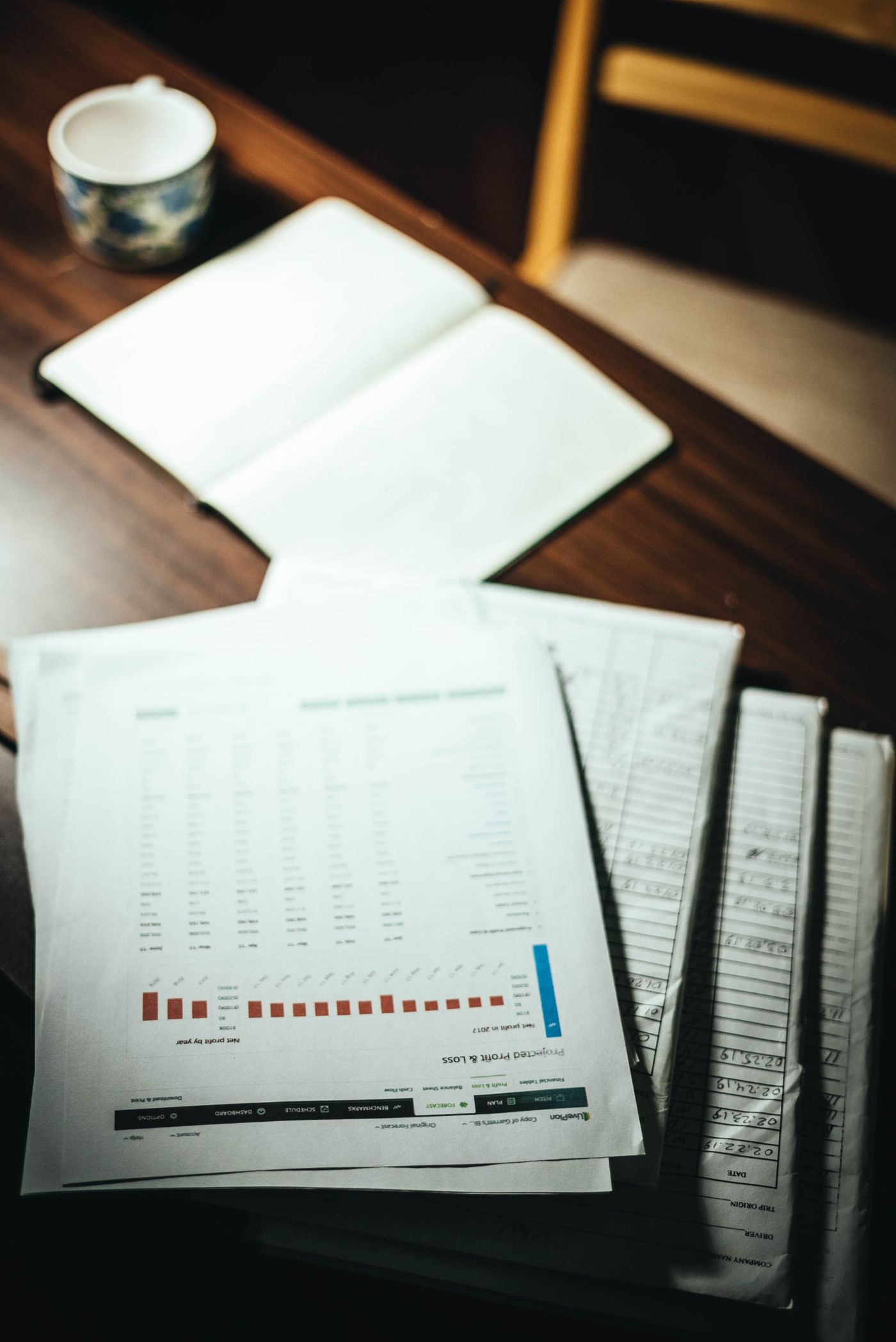 Une pile de documents et un carnet ouvert sur un bureau