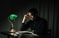 Wistful man with documents at table in dark room