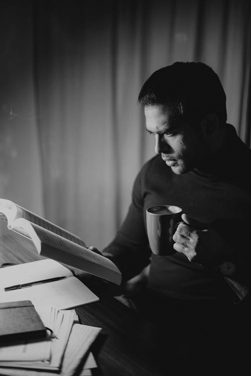 Frowning man reading book late at night