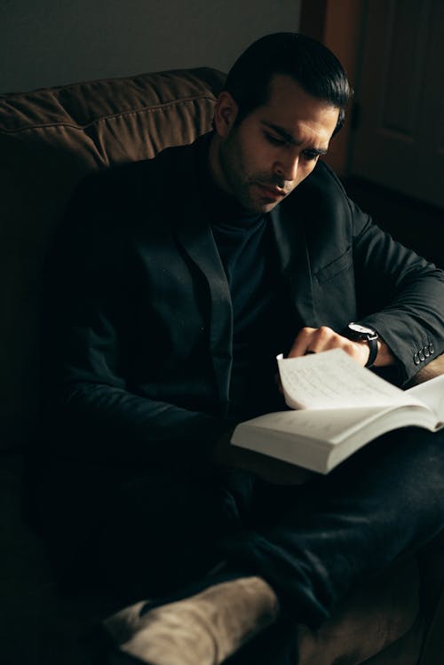 Formal serious man reading book on sofa