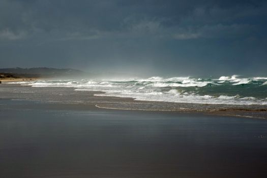 Stormy waves crash on Marcoola Beach in Queensland, Australia under dark skies.