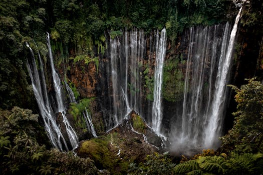Stunning view of Tumpak Sewu Waterfall cascading in a lush jungle setting in East Java, Indonesia.