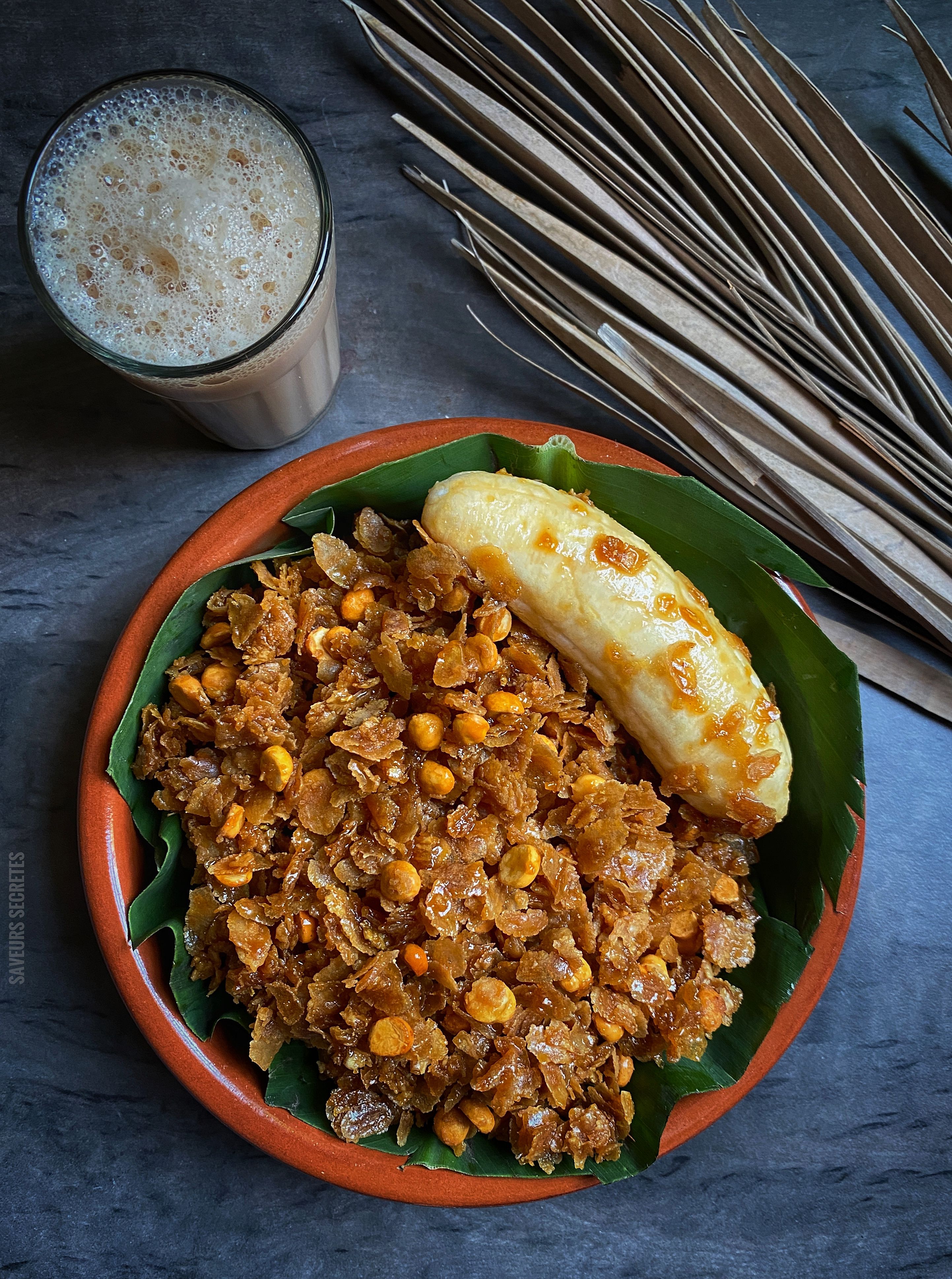 Top view of a bowl filled with cornflakes, a banana, and a glass of milk tea.