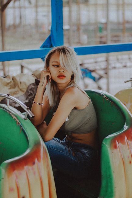 Young blonde woman relaxing on a colorful ride at an amusement park in daytime.
