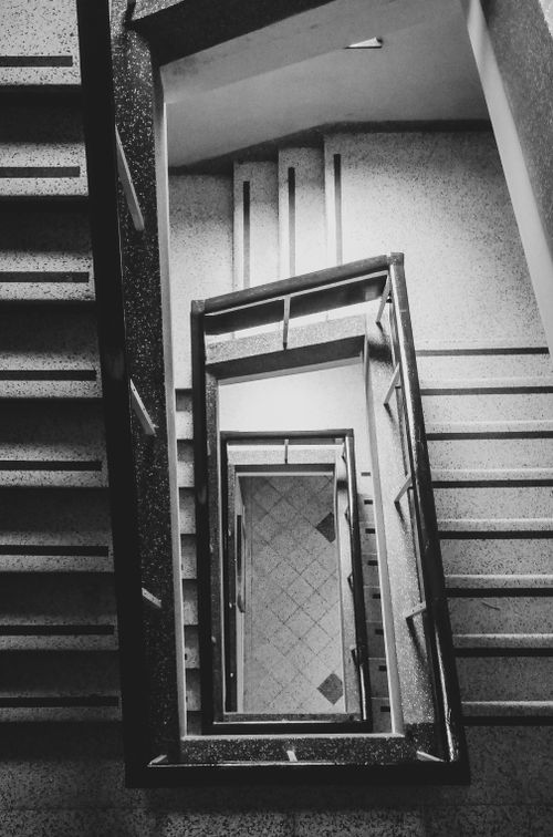 Free A captivating overhead view of a spiral staircase in monochrome, emphasizing architectural design. Stock Photo