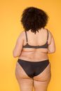Back view of anonymous obese woman in black bra and bikini with Afro hairstyle