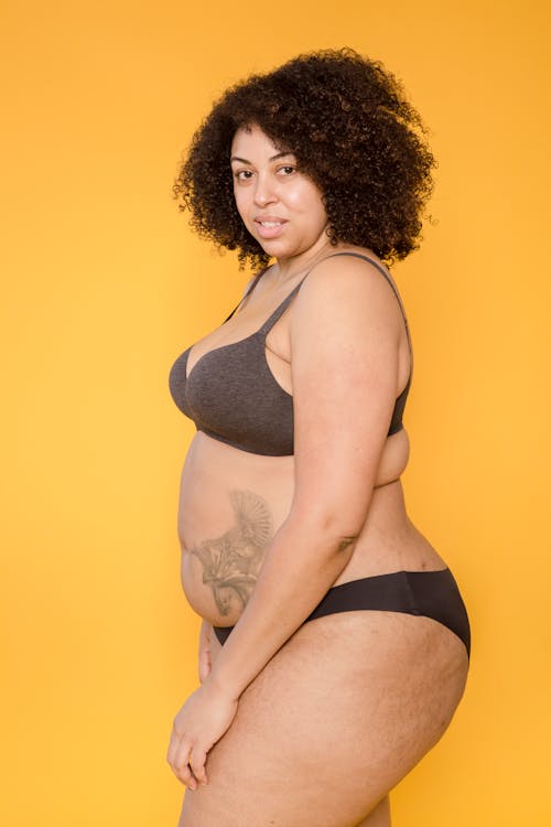Overweight ethnic model in lingerie on yellow background