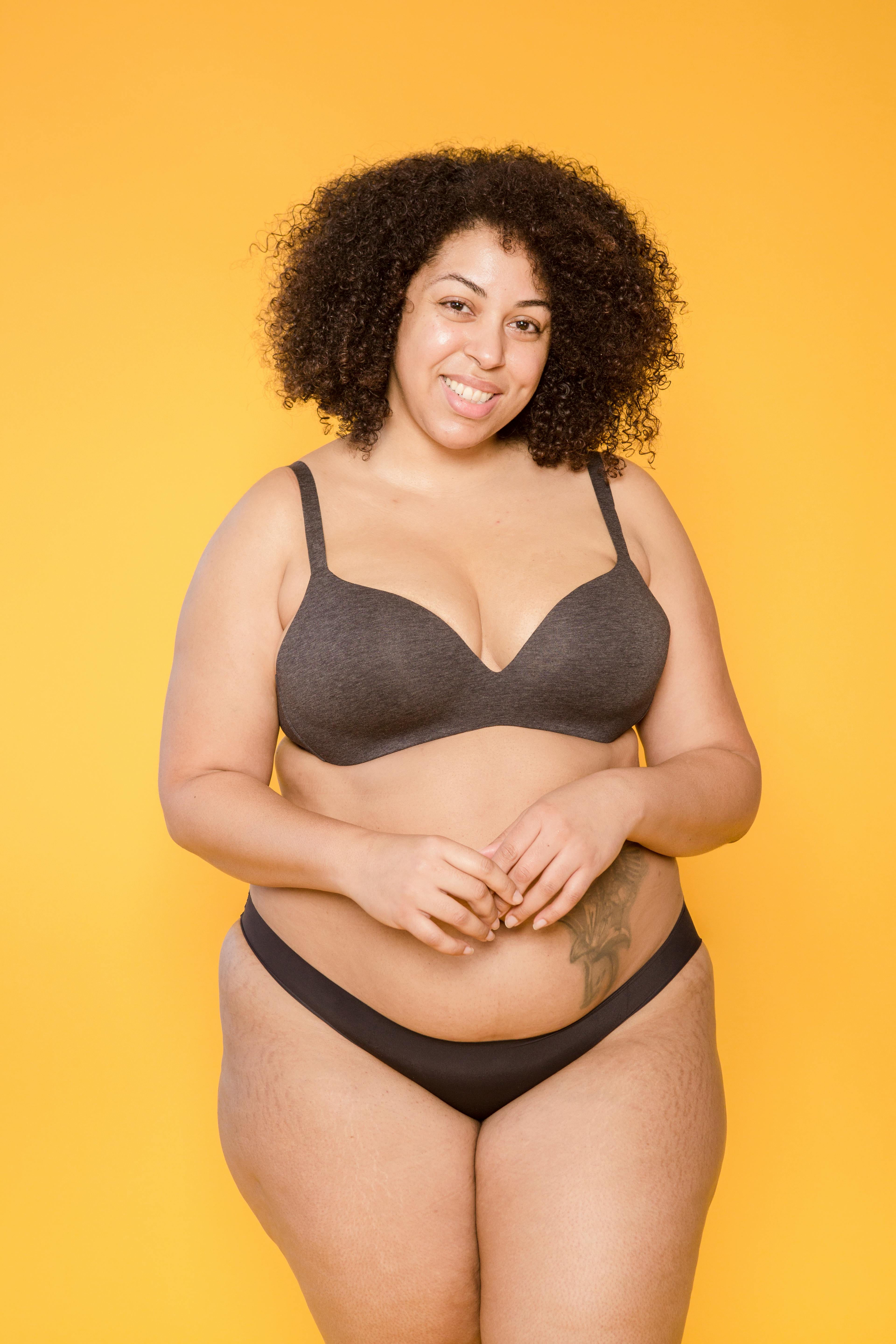 Smiling plump ethnic model in lingerie with tattoo  Free Stock Photo