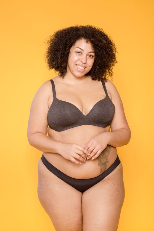 Free Cheerful obese African American woman in brassiere and panties with Afro hairstyle looking at camera on yellow background Stock Photo