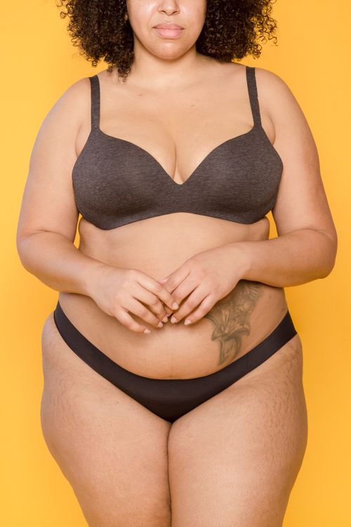 Free Crop anonymous plump ethnic woman in bra and bikini with tattoo and curly hair on yellow background Stock Photo