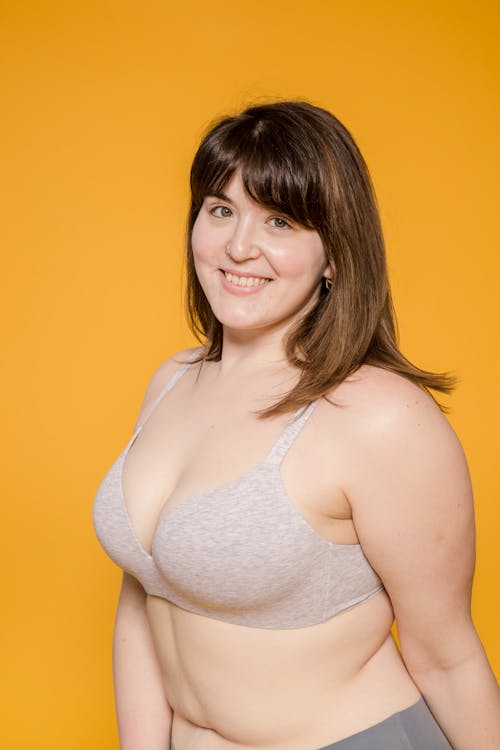 Plus size ethnic female in bra with brown hair looking at camera with toothy smile
