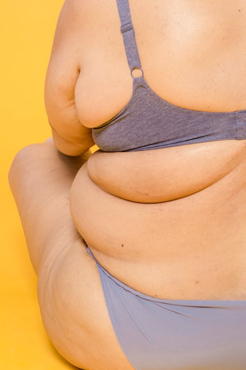 Crop obese model in lingerie on yellow background