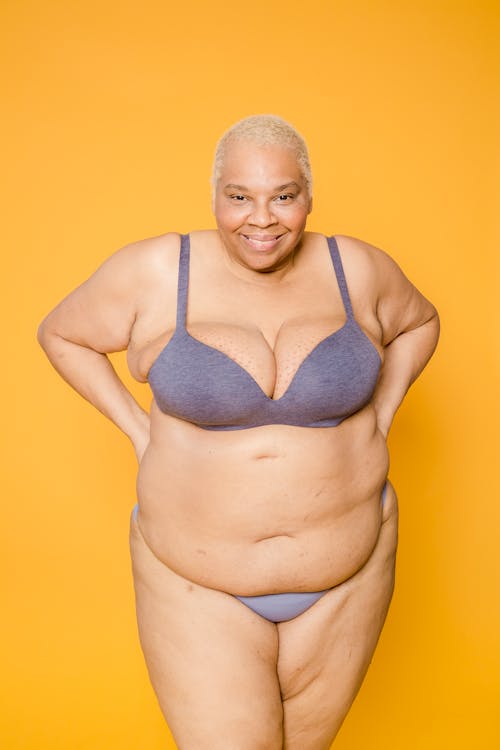 Cheerful plump diverse models in underclothes on yellow background