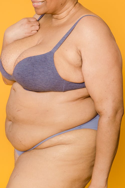 Crop obese model in underwear on yellow background