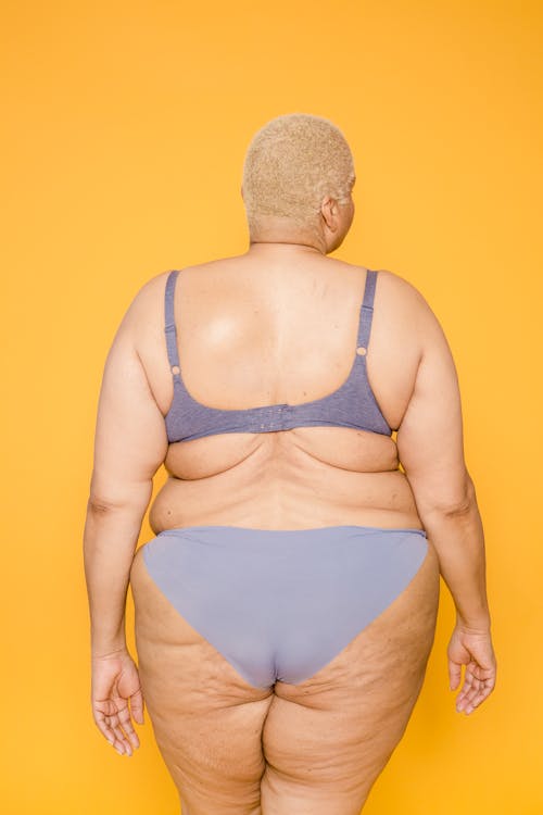 Free Back view of anonymous overweight woman in underwear with cellulite on thighs and skin folds on back Stock Photo
