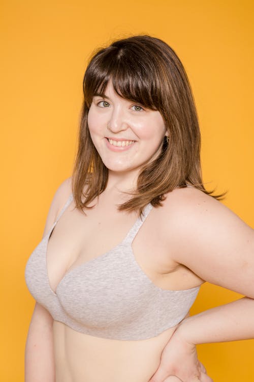 Cheerful overweight Asian model in bra on yellow background