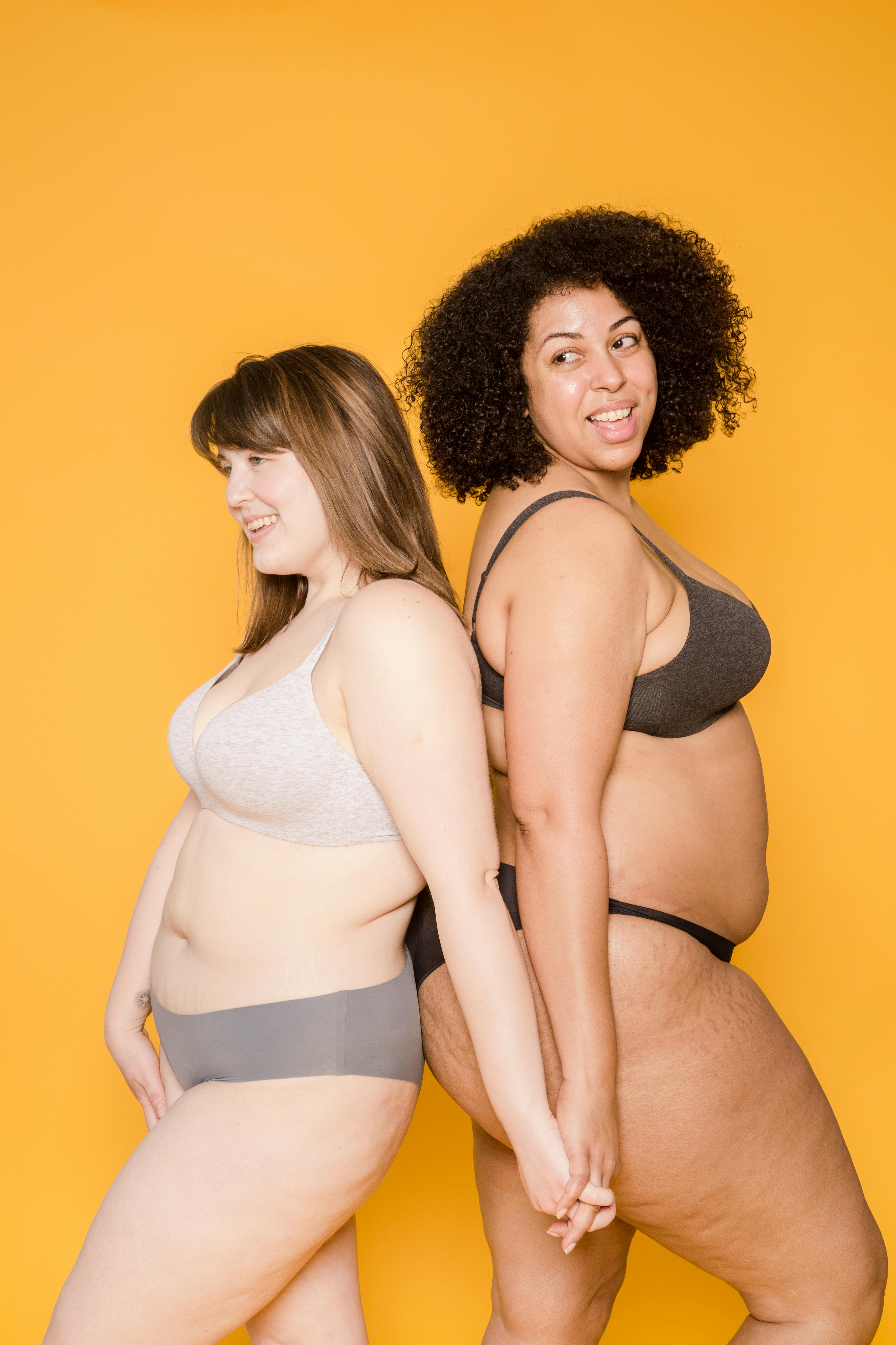 Cheerful plump diverse models in underclothes on yellow background