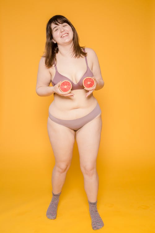 Happy plump Asian model in lingerie with grapefruit halves