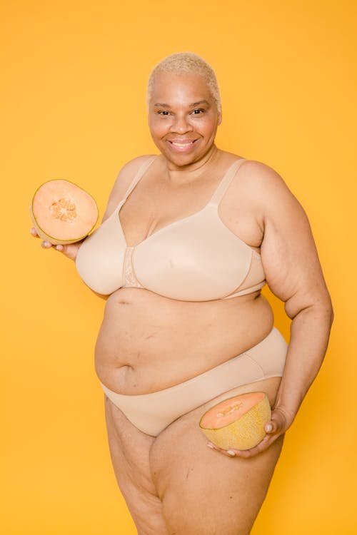 Smiling overweight ethnic model in lingerie with cut melon