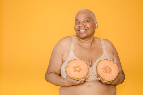 Smiling overweight African American model in bra with cut melon
