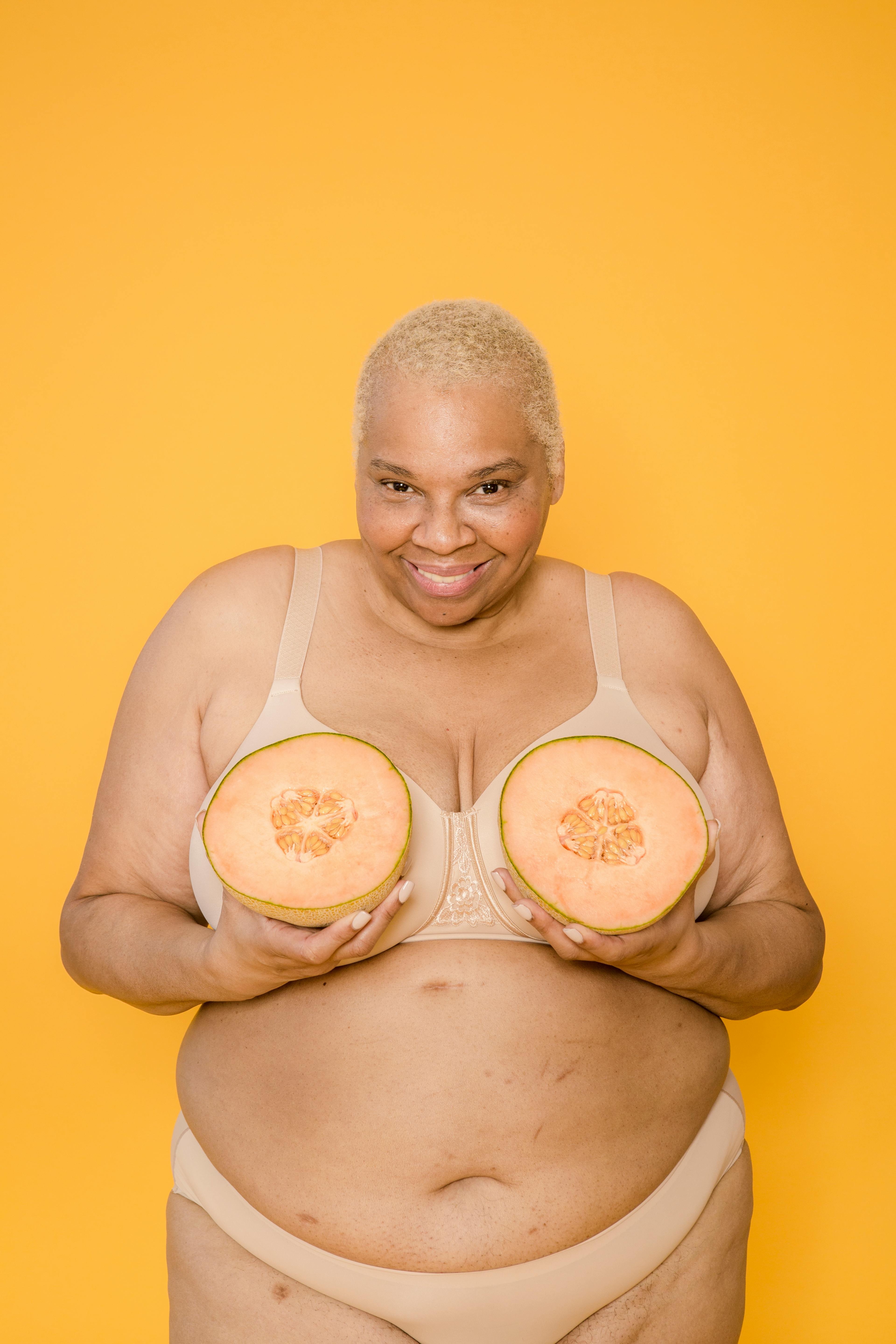 Cheerful overweight ethnic woman in underclothes with cut melon