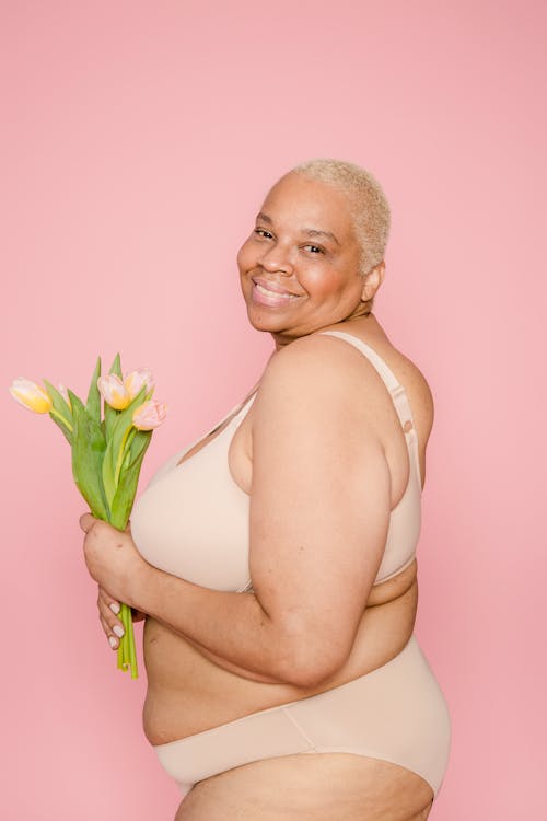 Smiling overweight black woman in underwear with flowers